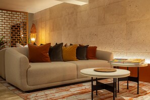Un soggiorno moderno con un divano color beige, un tavolino rotondo e un tappeto decorato.