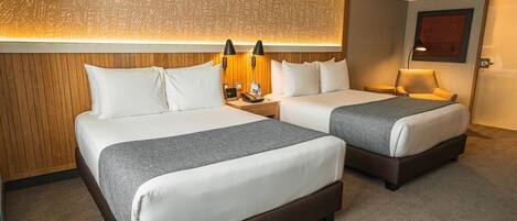 A hotel room with two beds, a wooden headboard, a patterned wall, and a carpeted floor.