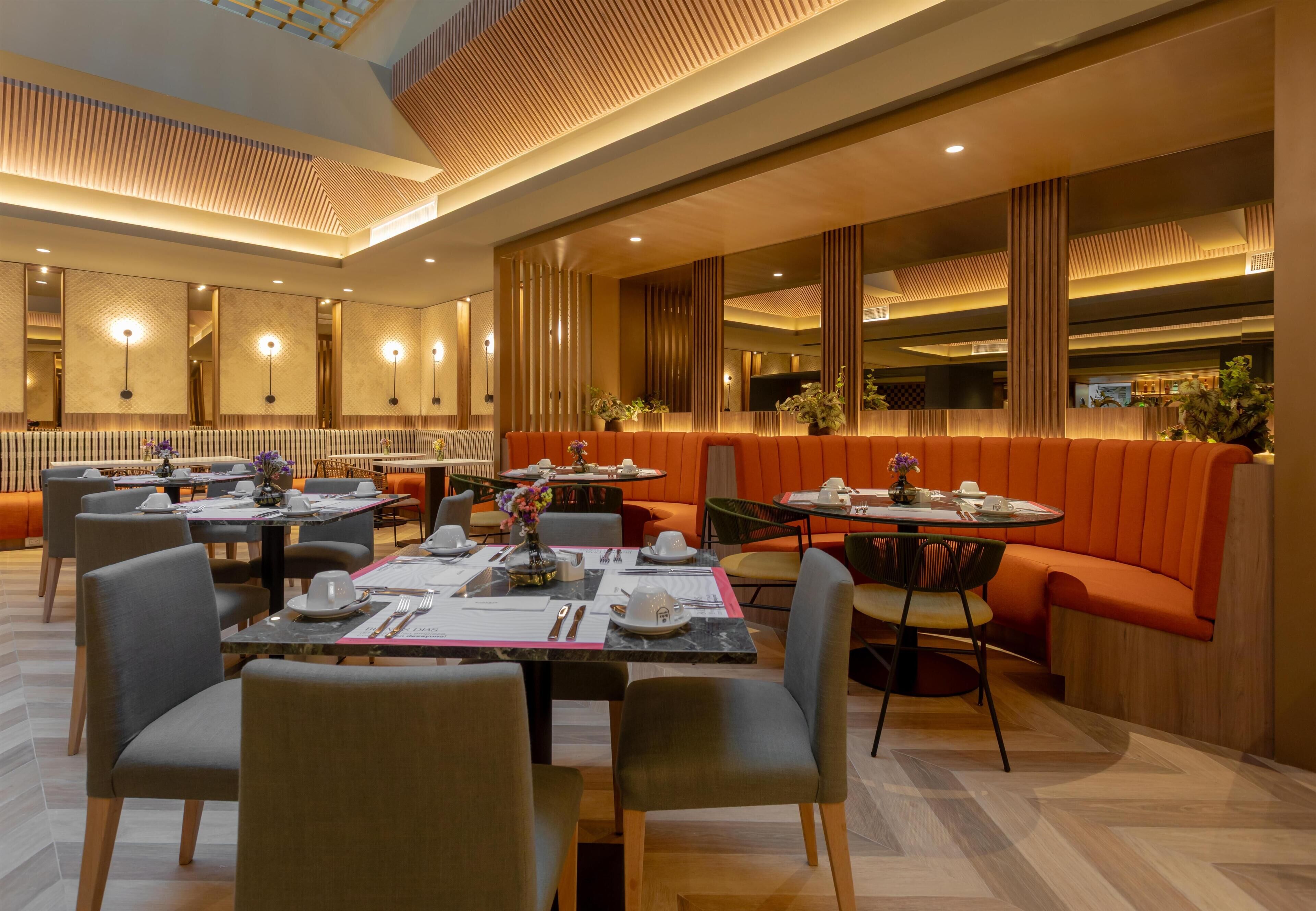 A modern restaurant with high ceilings, recessed lighting, and a mix of seating options including tables and booths.