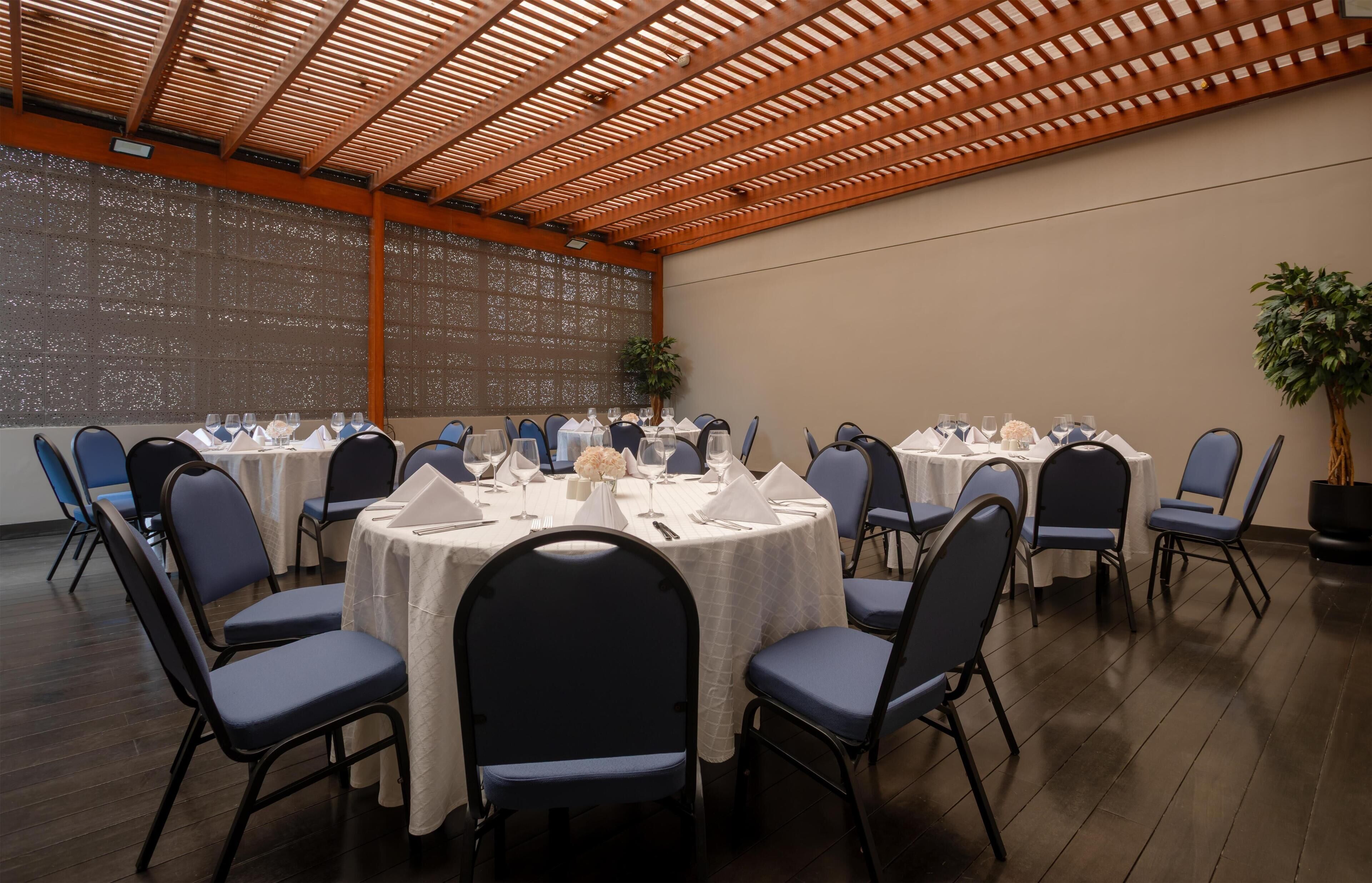 A conference room with round tables, blue chairs, and white tablecloths.