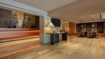 A modern hotel lobby with a reception desk, seating area, and a large wall with a textured design.
