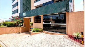 A modern building with a ground-level entrance, a visible address number, and a landscaped area with plants. - Sea View Apartment in the Heart of Rio Vermelho with Maid (Salvador)