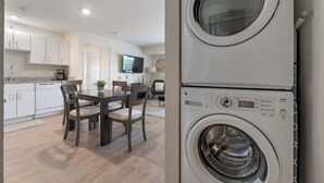 Une cuisine moderne avec des meubles blancs, une table à manger avec des chaises et un lave-linge encastré.