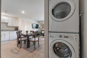 A modern kitchen with white cabinets, a dining table with chairs, and a built-in washing machine. - RD402 - Home|Yard|12mi to Convention Ctr|Sleeps 6 (Richardson)