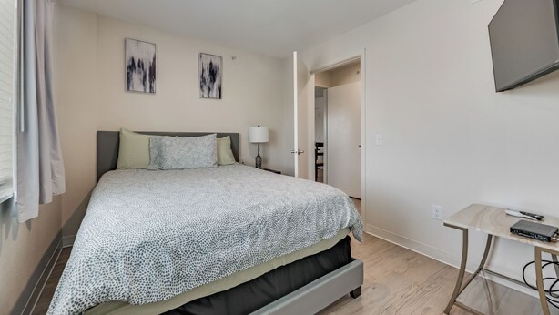 Une chambre à coucher avec un lit, un bureau et un téléviseur fixé au mur.