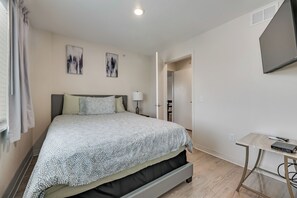 Une chambre à coucher avec un lit, un bureau et un téléviseur fixé au mur.