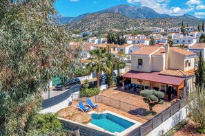 Un quartier résidentiel doté d’une piscine, de chaises longues bleues et offrant une vue sur les montagnes.