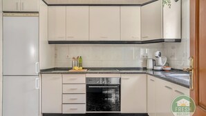 A kitchen with white cabinets, a black oven, and a marble floor. - Casa del Barco: Villa with Private Retreat Vibes (Guaro)