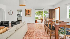 A modern living room with a sofa, chairs, a dining table, and a kitchen in the background. - Casa del Barco: Villa with Private Retreat Vibes (Guaro)