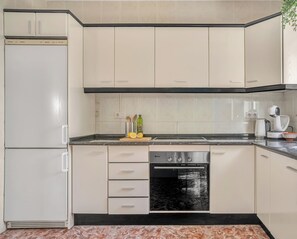 A kitchen with white cabinets, a black oven, and a marble floor. - Casa del Barco: Villa with Private Retreat Vibes (Guaro)