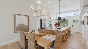 A modern kitchen with white cabinets, a central island, and pendant lighting. - Coastal Oasis, Lovely 3-bedroom condo with AC in Holmes Beach (FL - Holmes Beach)