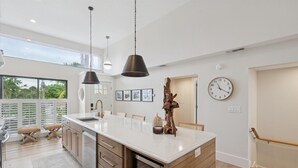 A modern kitchen with a large island, pendant lights, and a view of the outdoors. - Coastal Oasis, Lovely 3-bedroom condo with AC in Holmes Beach (FL - Holmes Beach)