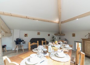 Ein Essbereich mit einem Holztisch, gedeckt für das Frühstück, umgeben von Stühlen, mit einer Couch und einem Schrank im Hintergrund.