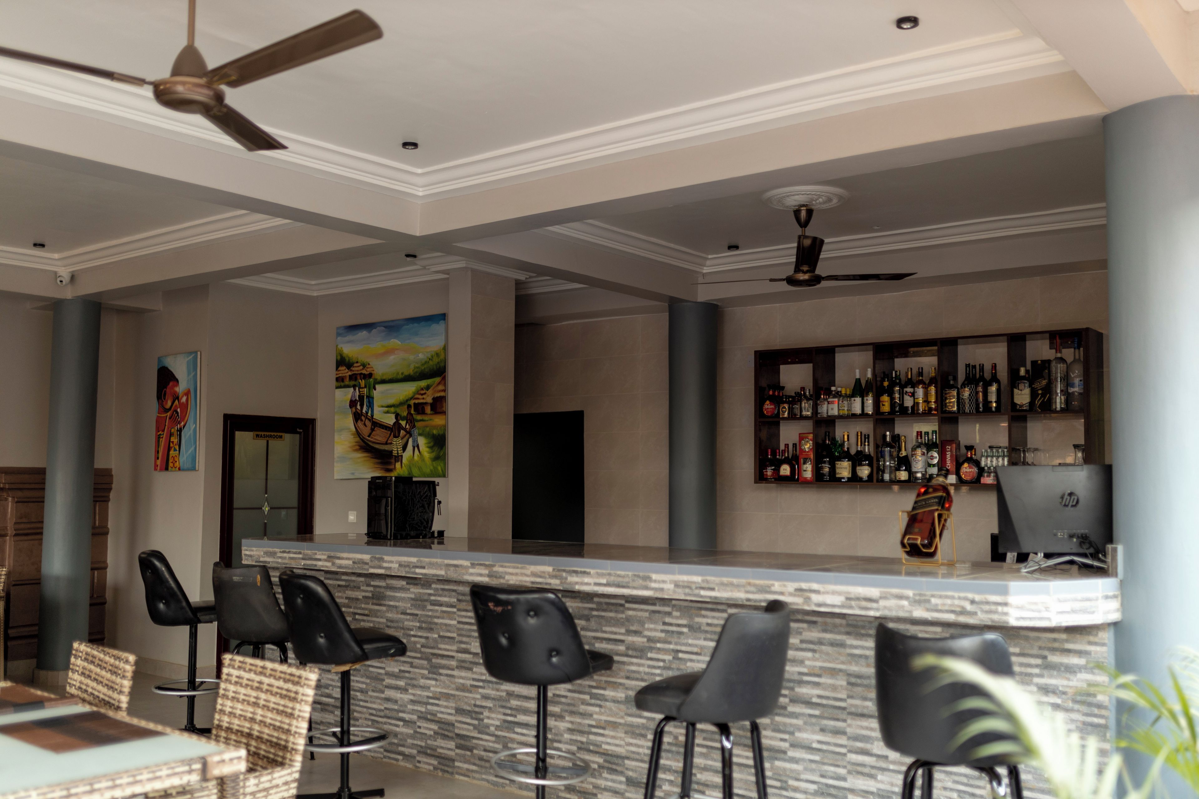 A bar area with a counter, bar stools, and a variety of bottles.