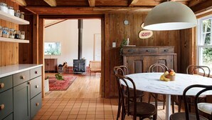 Eine rustikale Küche mit Holzbalken, einem großen Fenster und einem Essbereich mit einem Marmortisch.