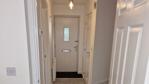 A hallway with a tiled floor, white walls, and a door at the end. - NightRest Homes Orchid NEC Free Parking  2 Toilets (West Midlands)
