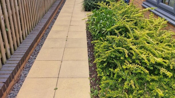 A pathway leading to a residential building with a wooden fence on one side and a well-maintained garden on the other. - NightRest Homes Orchid NEC Free Parking  2 Toilets (West Midlands)