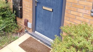 A blue door with a small window, a mailbox, and a doorbell on a brick wall. - NightRest Homes Orchid NEC Free Parking  2 Toilets (West Midlands)
