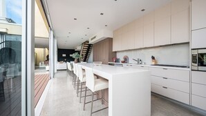 A modern kitchen with a central island, bar stools, and a view of the outdoor deck.