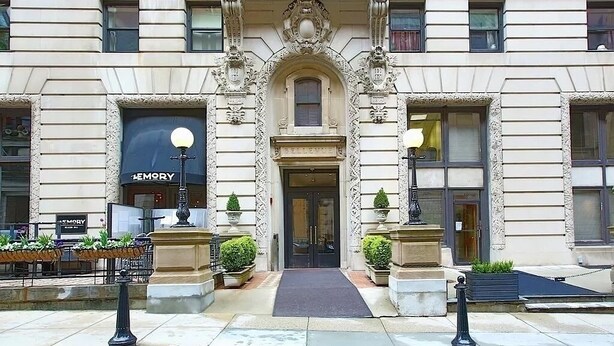 A classical building with a central entrance, ornate columns, and a sign for 'MEMORY' on the left. - Elegant Mid-Century Modern Condo — Fully Furnished Luxury in the Heart of Boston (Boston)
