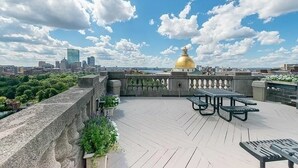 A rooftop terrace with a golden dome, a city skyline in the background, and a view of the river. - Elegant Mid-Century Modern Condo — Fully Furnished Luxury in the Heart of Boston (Boston)