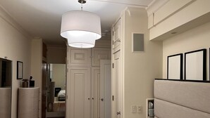 A bedroom with a bed, a dresser, a mirror, a wardrobe, and a ceiling light. - Elegant Mid-Century Modern Condo — Fully Furnished Luxury in the Heart of Boston (Boston)