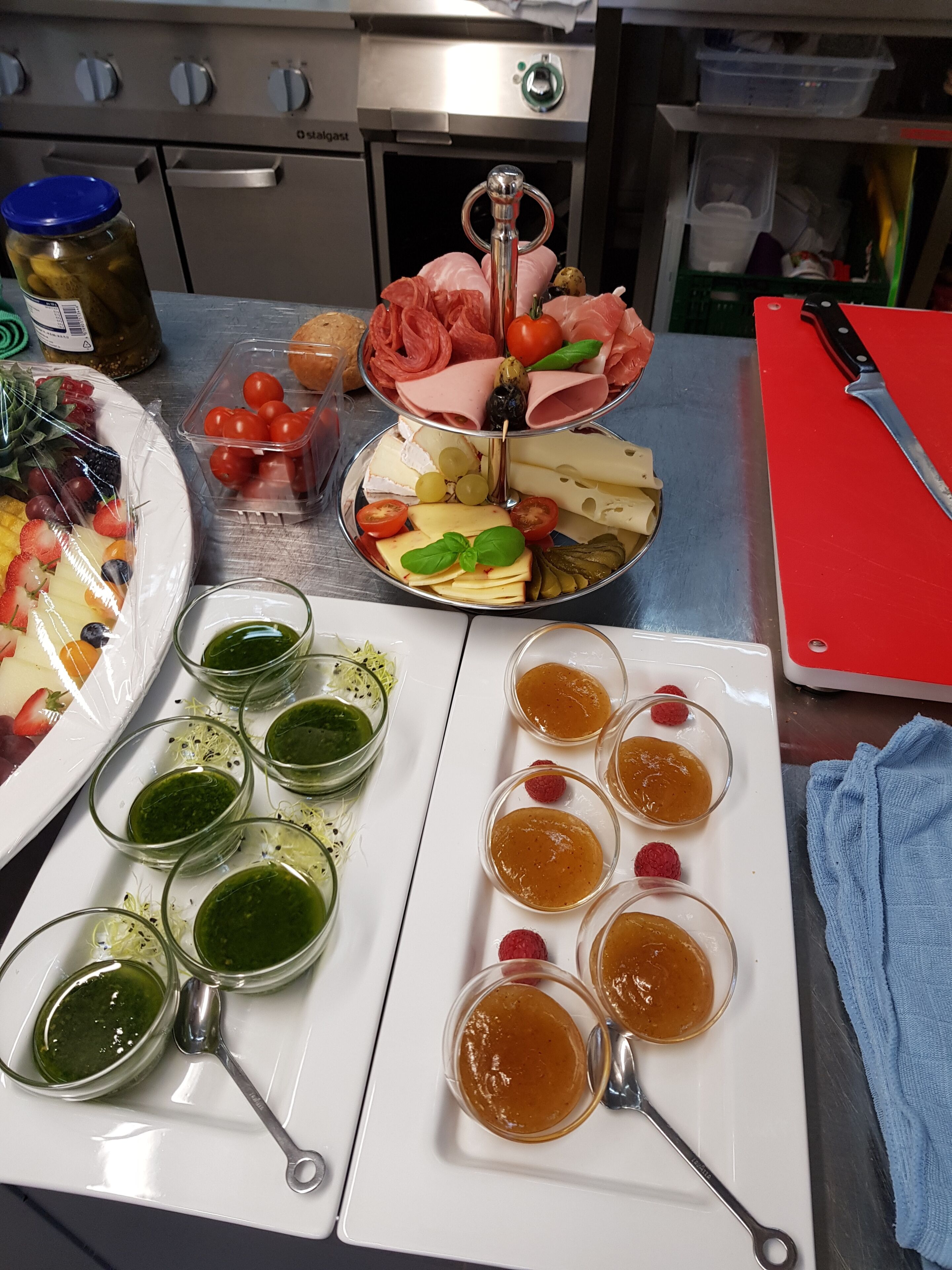 A kitchen counter with a variety of food items including a platter of cheeses, meats, and fruits, as well as several small bowls containing different sauces.