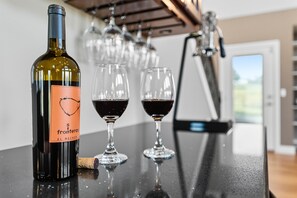 A bottle of wine and two glasses on a counter.