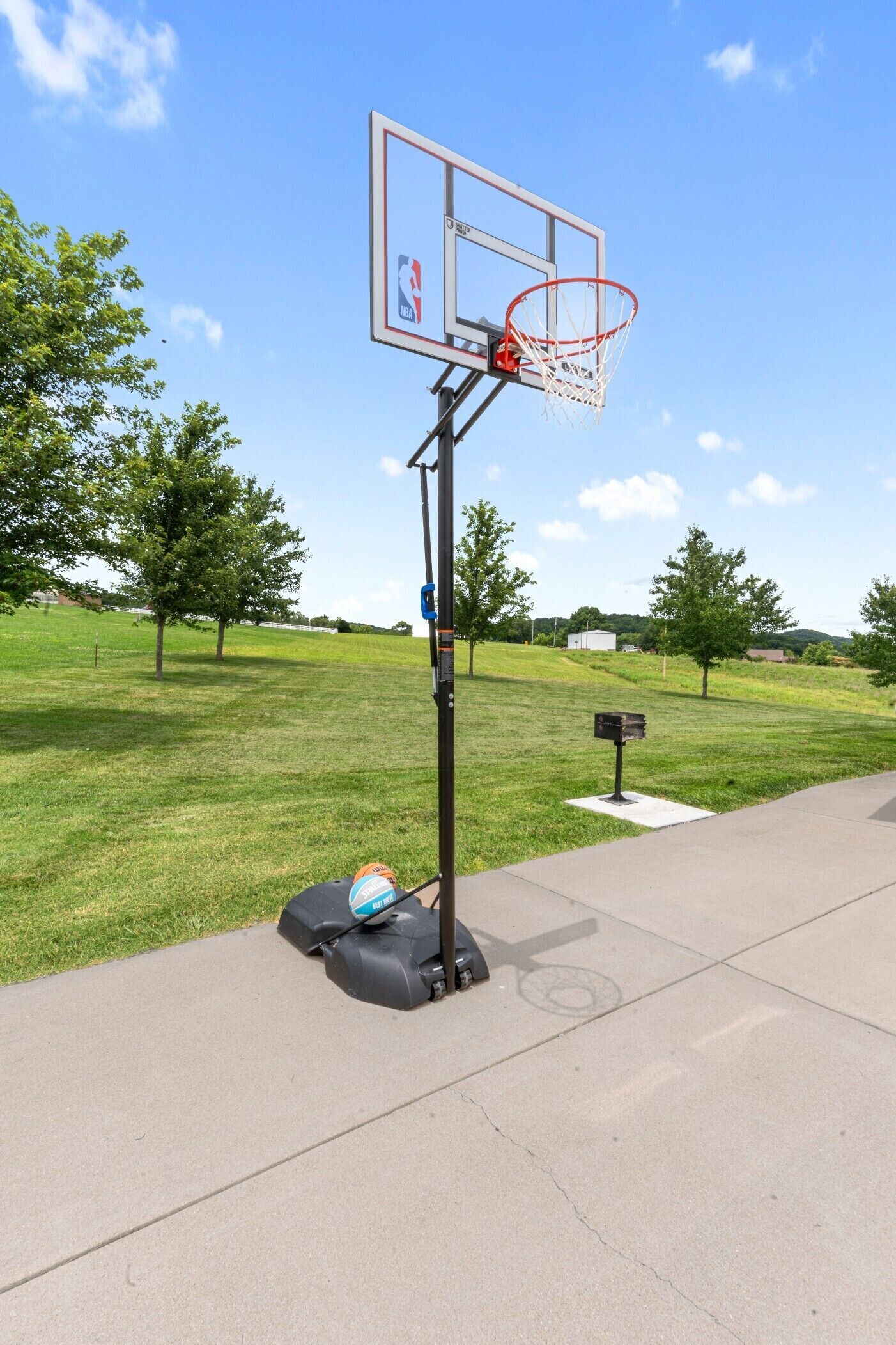 Un panier de basket avec un filet, un ballon de basket et une boîte aux lettres sur un trottoir.