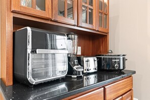 A kitchen with a toaster, blender, and crockpot on a black countertop.