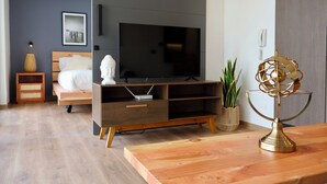 A modern bedroom with a bed, a TV, a wooden dresser, and a decorative lamp. - Corporate Stays Somma Asturias (Santiago)