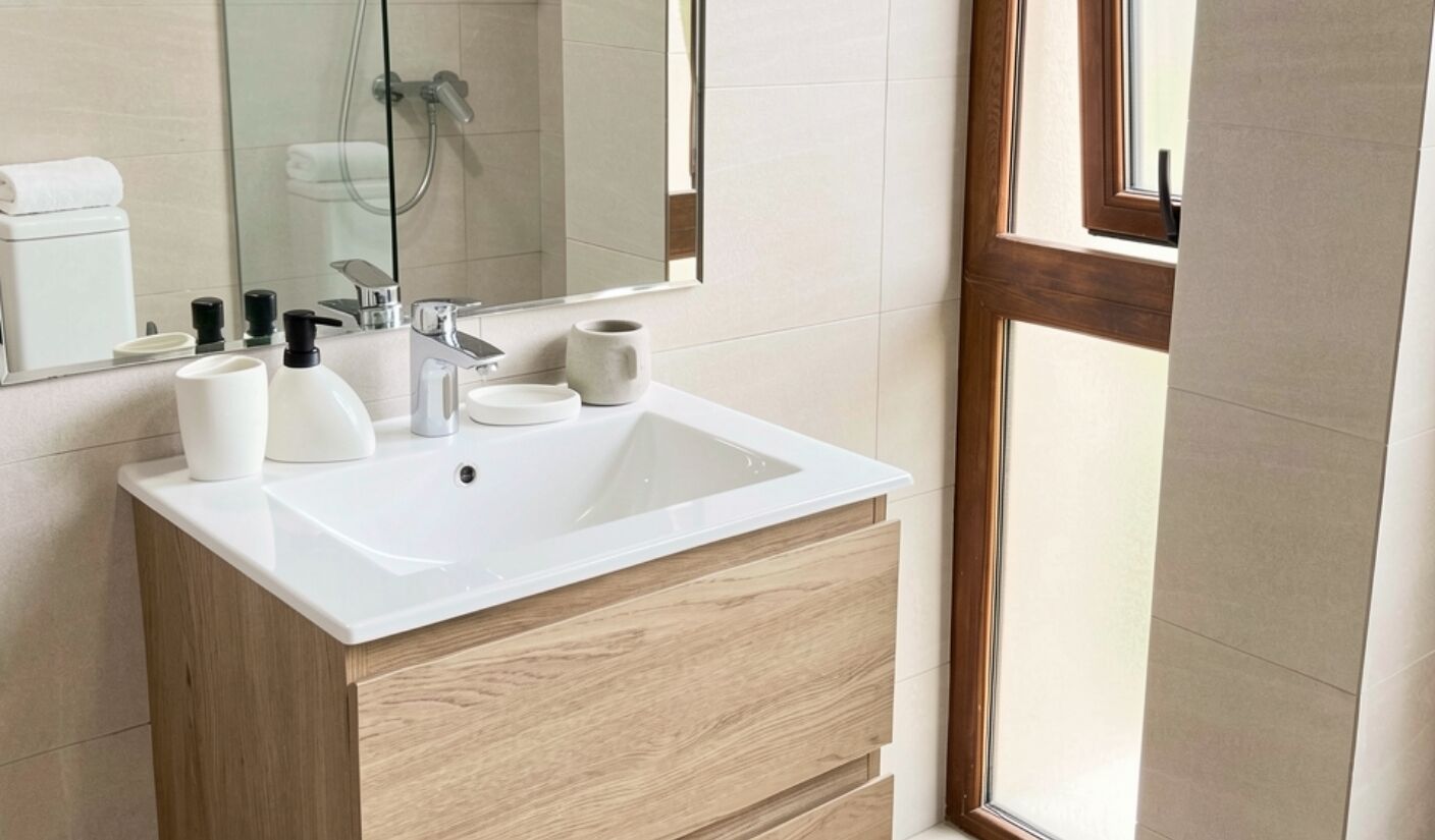 Une salle de bain avec un lavabo blanc, un meuble-lavabo en bois et un grand miroir.