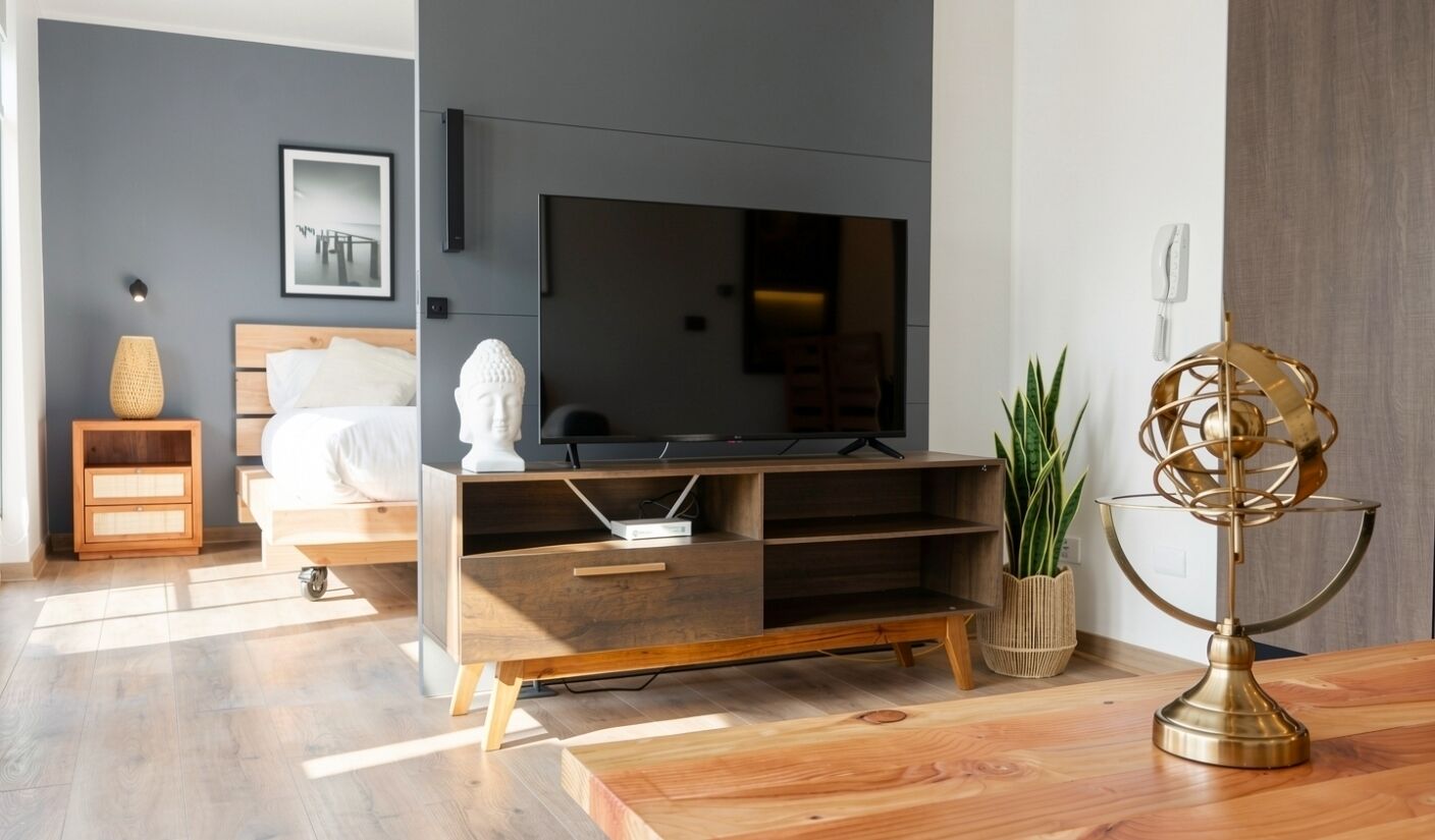 Una camera da letto moderna con una grande TV a schermo piatto, mobili in legno, un letto e un comodino con una lampada.