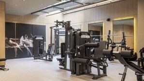 A modern gym with various exercise machines, a large mirror, and a wall-mounted poster. - Corporate Stays Somma Asturias (Santiago)