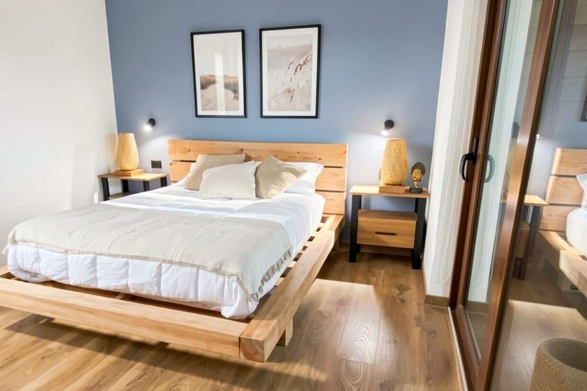 A bedroom with a wooden bed, two bedside tables, and wall-mounted lamps.