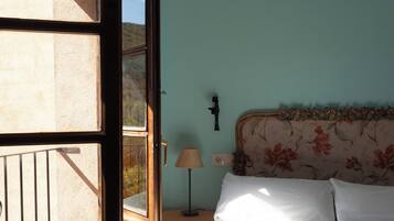 A bedroom with a bed, a nightstand, a lamp, and a view through an open door.