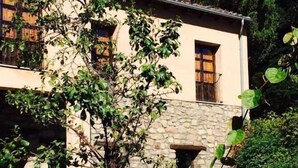 A stone building with a garden in front, featuring a tree and a small fountain. - hotel rural el jardin del conde (Peñacaballera)