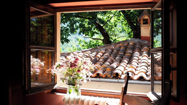 A window with a view of a tiled roof and a tree outside. - hotel rural el jardin del conde (Peñacaballera)