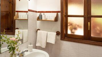 A bathroom with a white sink, a mirror, a window with frosted glass, and a towel rack.