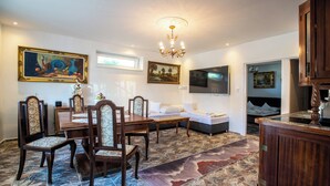 Un comedor con mesa y sillas de madera, un sofá y un televisor montado en la pared.