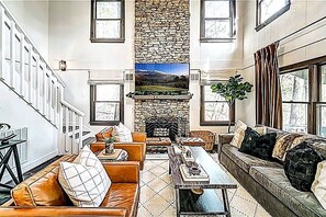 Una sala de estar con chimenea, sofá, una mesa de centro y una escalera.