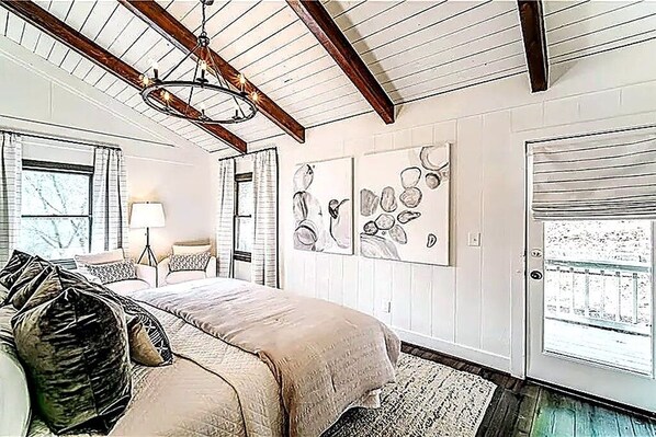 Un dormitorio con cama, candelabro, una puerta y obras de arte en la pared.