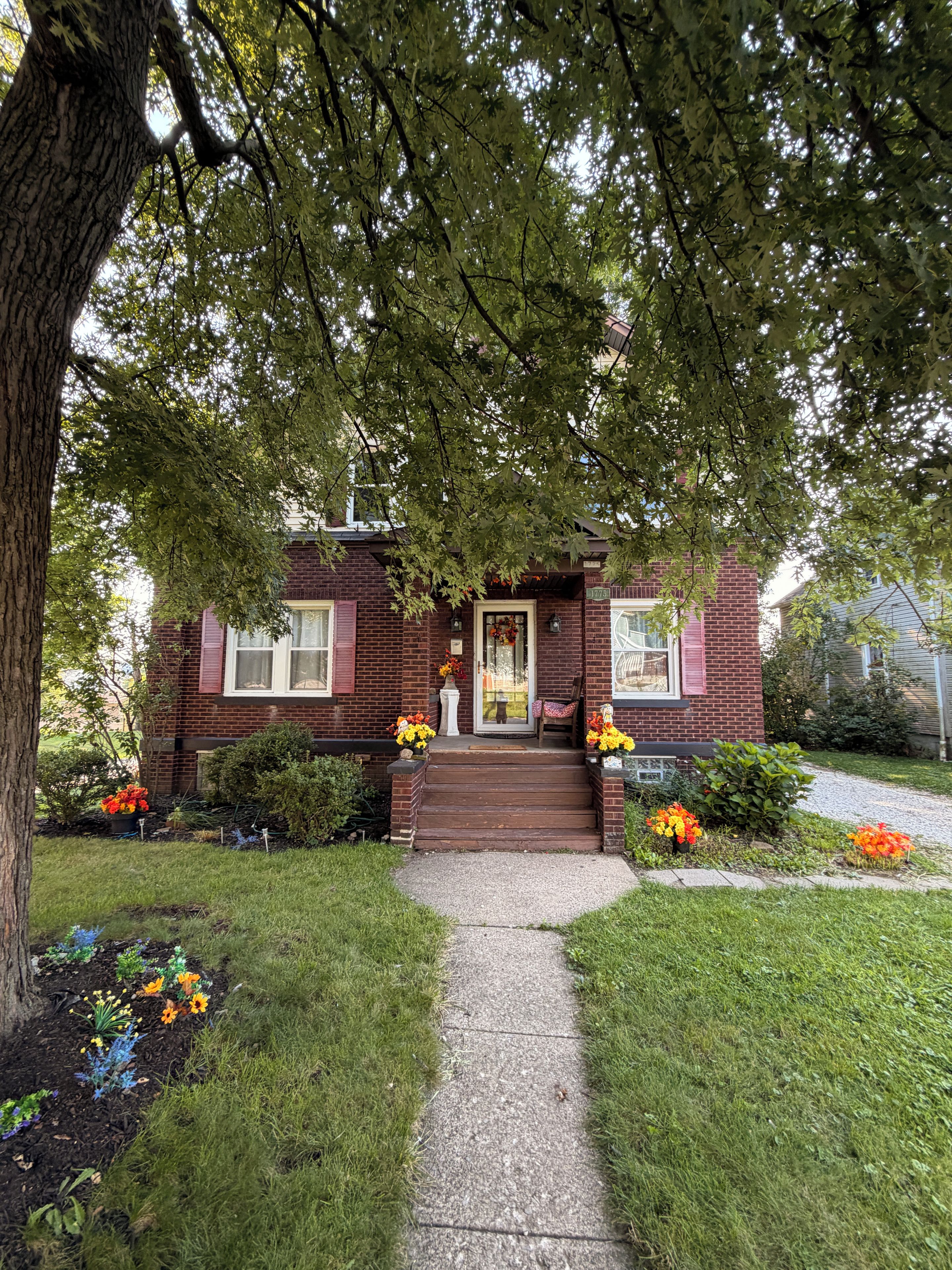 A brick house with a front porch, steps leading to the door, and a pathway.