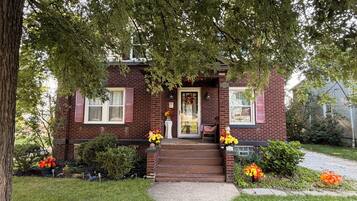 A brick house with a front porch, steps leading to the door, and a pathway.