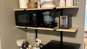 A kitchenette with a microwave, coffee maker, toaster, and a small refrigerator.
