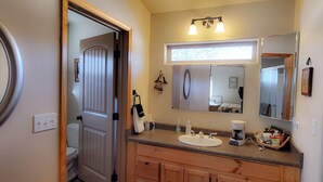 A bathroom with a sink, mirror, and a window above the mirror.