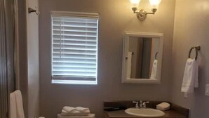 A bathroom with a toilet, sink, and mirror. - Pine Creek Cabins - Cabin 1 (Pine)