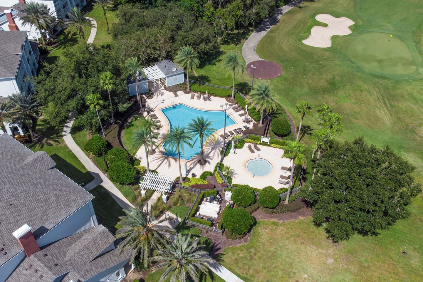 Un resort con piscina, campo de golf y una zona de piscina separada con sillas de sol.