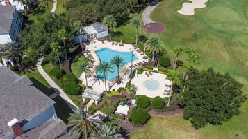 Un resort con piscina, campo de golf y una zona de piscina separada con sillas de sol.