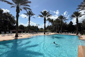 Una piscina con lettini e palme.
